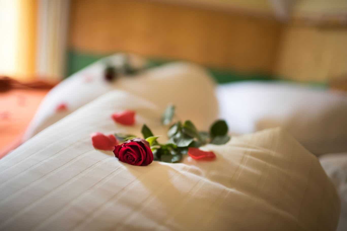 Stimmungsbild von einer roten Rose am Bett im Kuschel-Romantik-Zimmer im Thermenhof PuchasPLUS in Loipersdorf